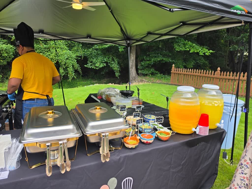 Taquiza station under a canopy with warm chafers, salsas and lemonade dispensers
