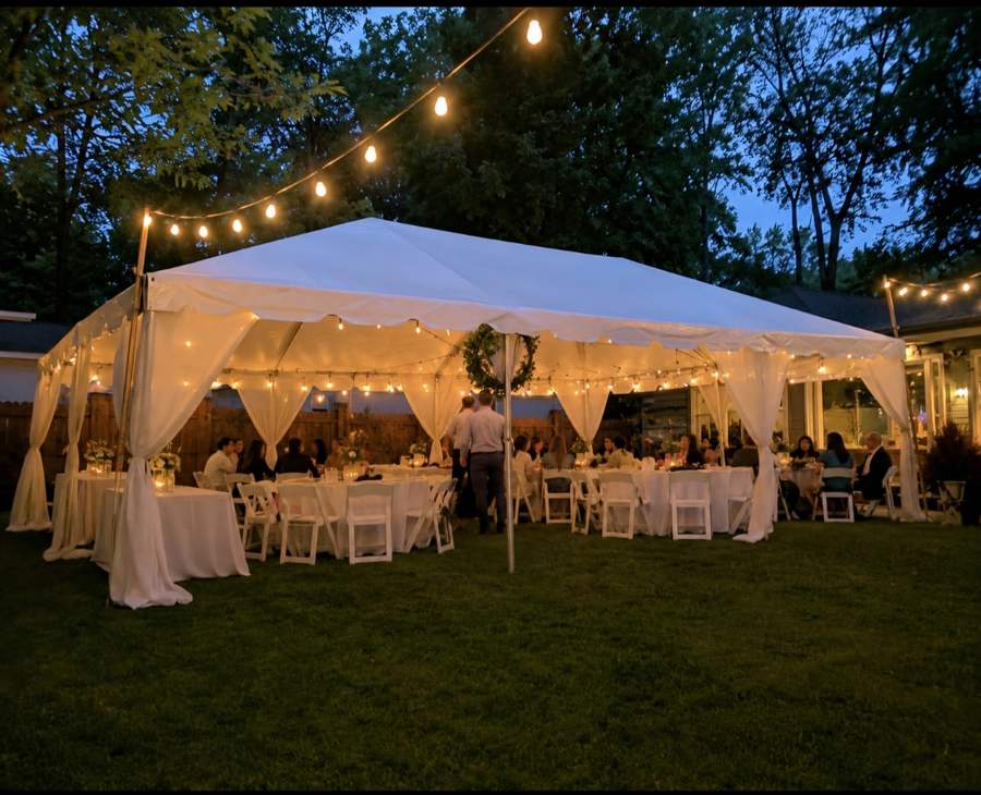 Draped tent with string lights at a backyard wedding reception