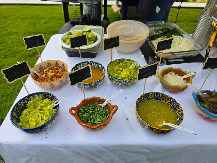 Bowls of guacamole, pico de gallo and salsas labelled on a buffet table